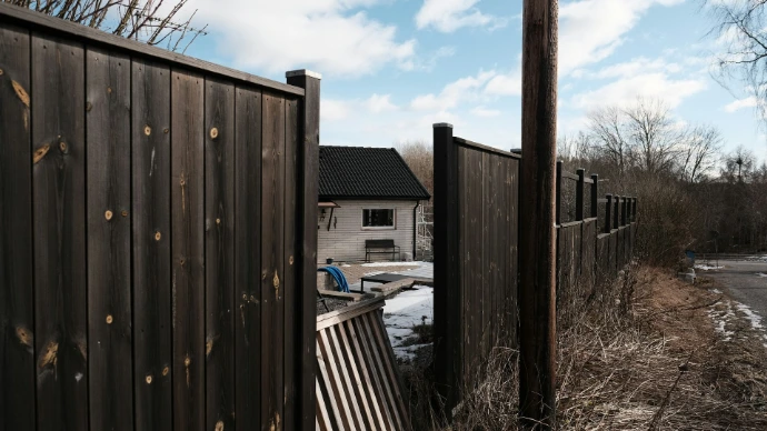 a open wooden fence with a house in the background