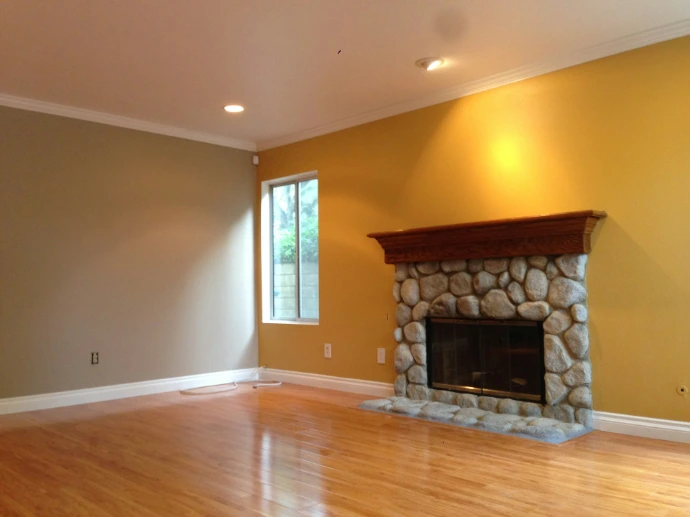 an empty living room with a fireplace and hard wood floors