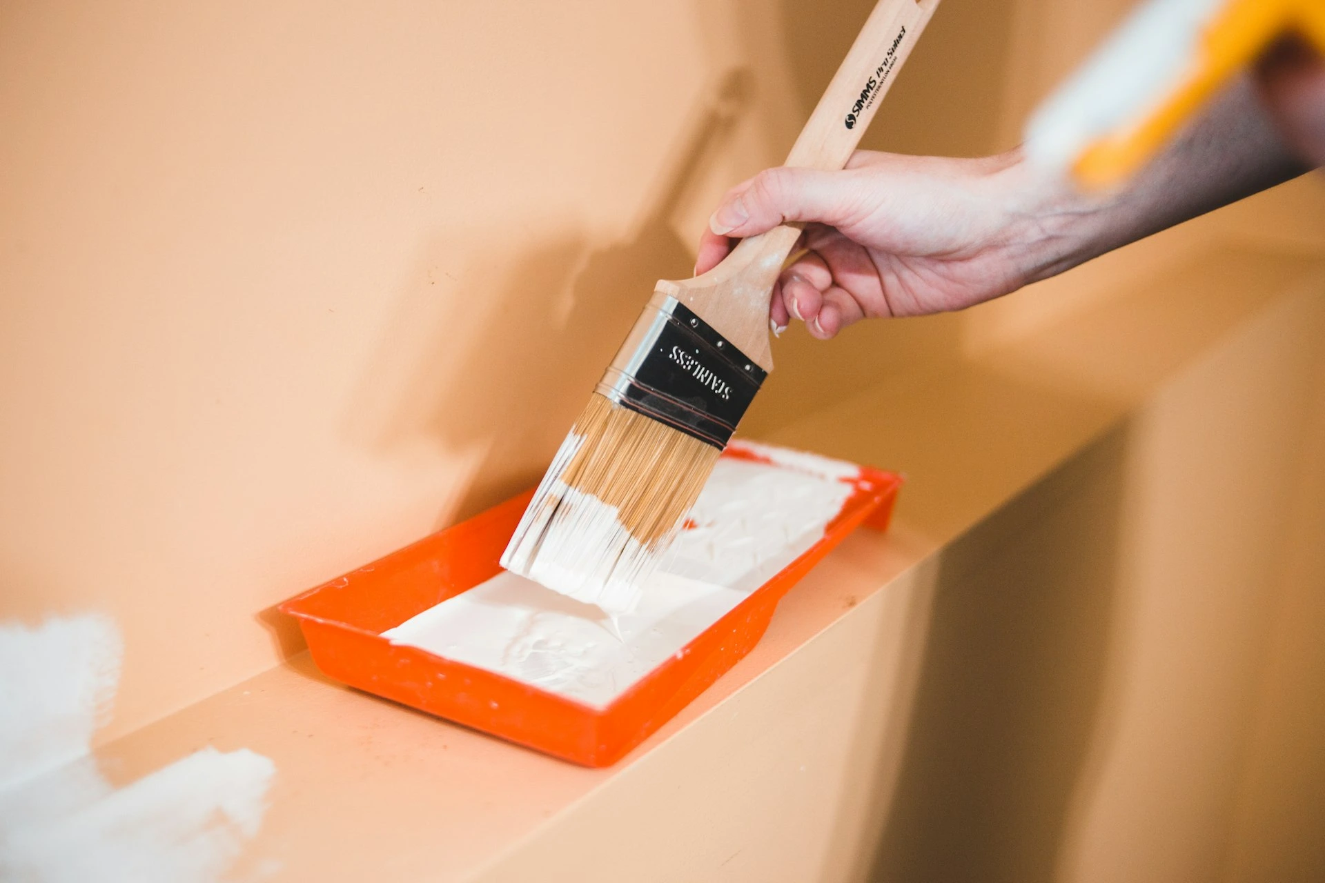 hand holding paintbrush over paint