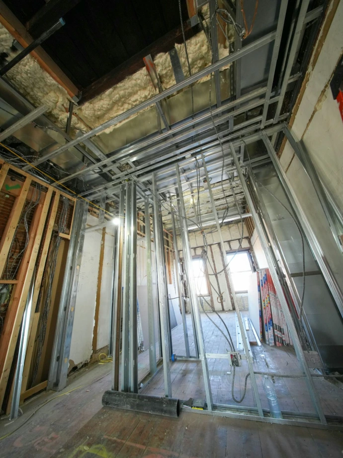 Interior construction with metal framing and exposed wires.