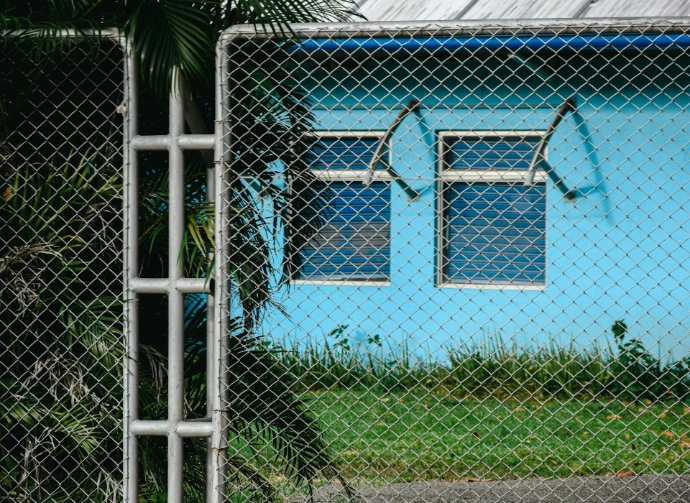 blue house behind Chain-link fence