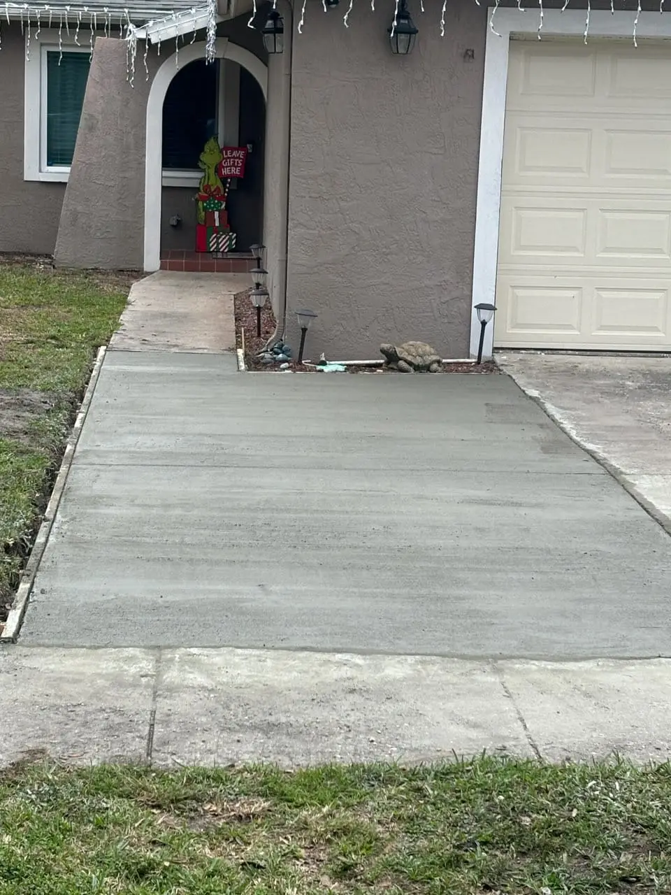 New concrete driveway slab installed in front of a residential garage